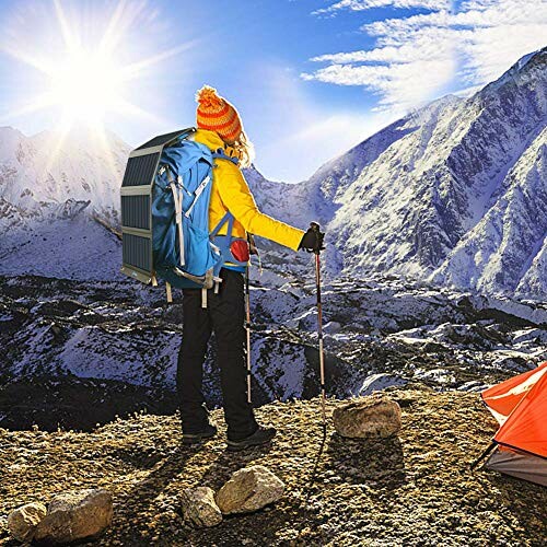 Hiker with backpack and trekking poles on a snowy mountain landscape.